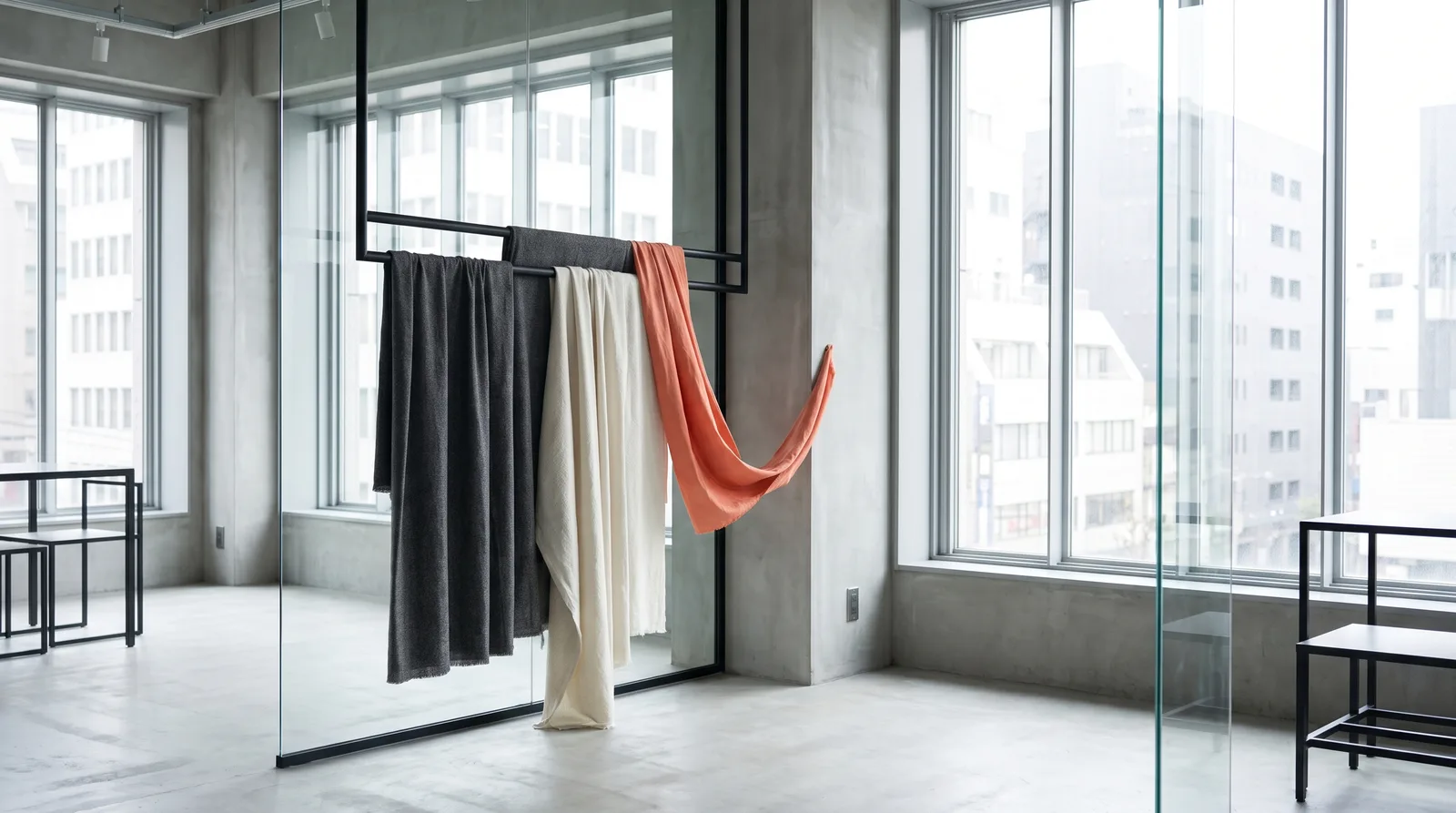 Scorcio di atelier moderno con rotoli di tessuto fluido appesi, atmosfera naturale